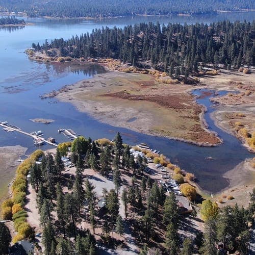 Grout Bay in autumn from above: golden willows, boat docks, and shallow channels winding toward the lake.