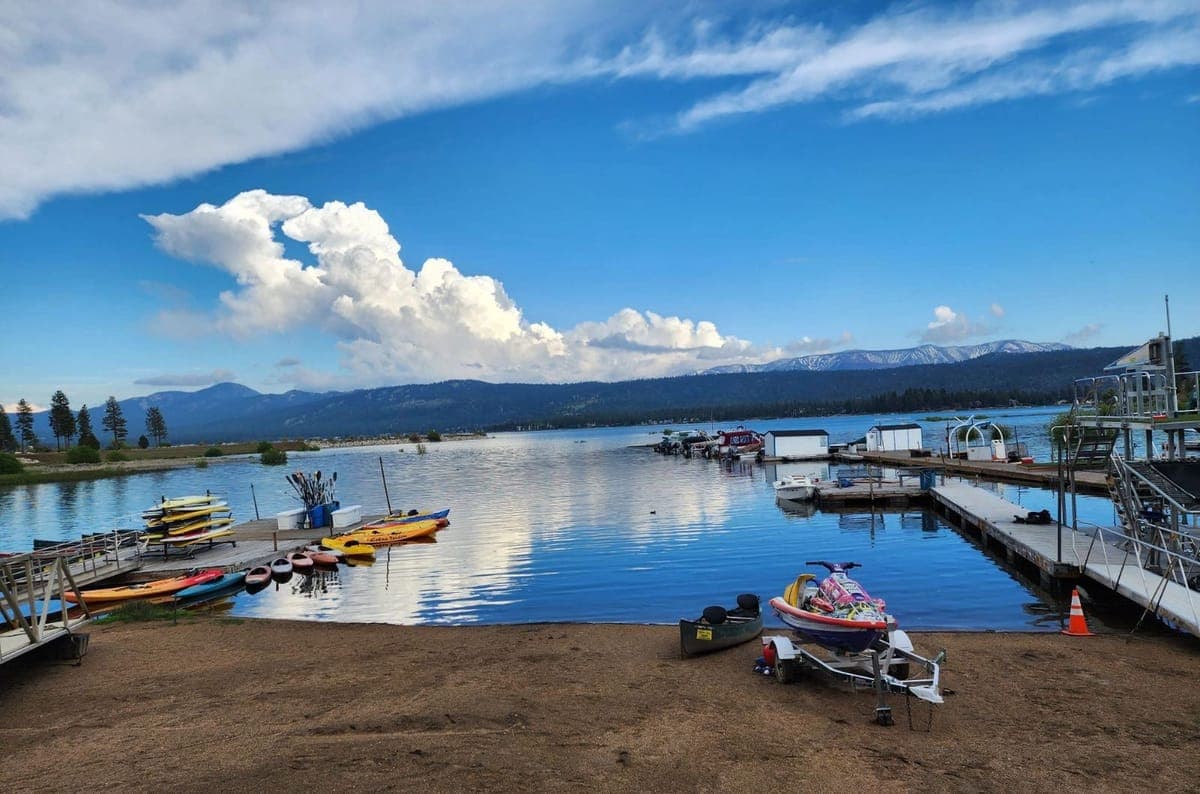 Kayaks and paddle boards on the beach at Grout Bay, with the harbor, the lake and the far ridgeline beyond.